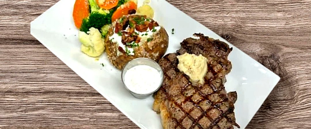 16 oz ribeye with baked potato and vegetables at Matera Grill