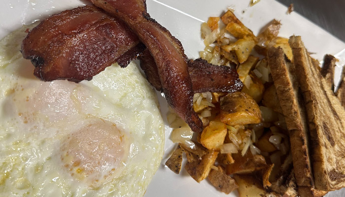 Matera Italian Breakfast Menu: Two fried eggs, crispy bacon, potatoes with onions, and toast.