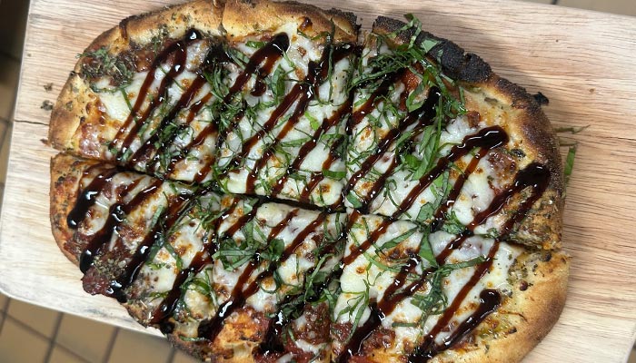 Rectangular flatbread pizza from Matera Italian Menu Pizza Pasta & More in Escanaba, topped with basil.