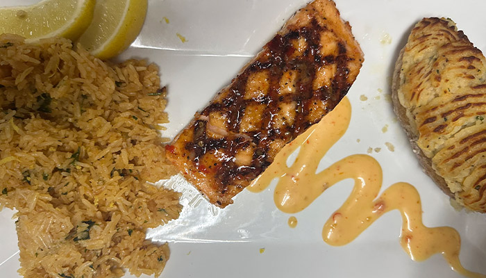 Grilled salmon with rice, lemon wedges, and a twice-baked potato at Matera Italian Menu Escanaba.