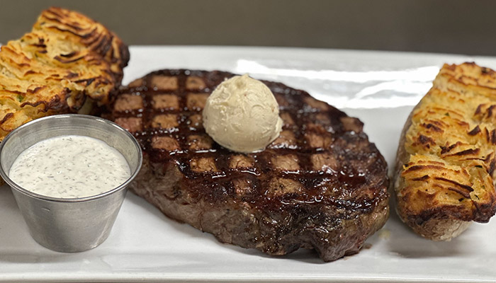 Grilled steak with butter, potato halves, and sauce at Matera Italian Menu Pizza Pasta & More Escanaba.